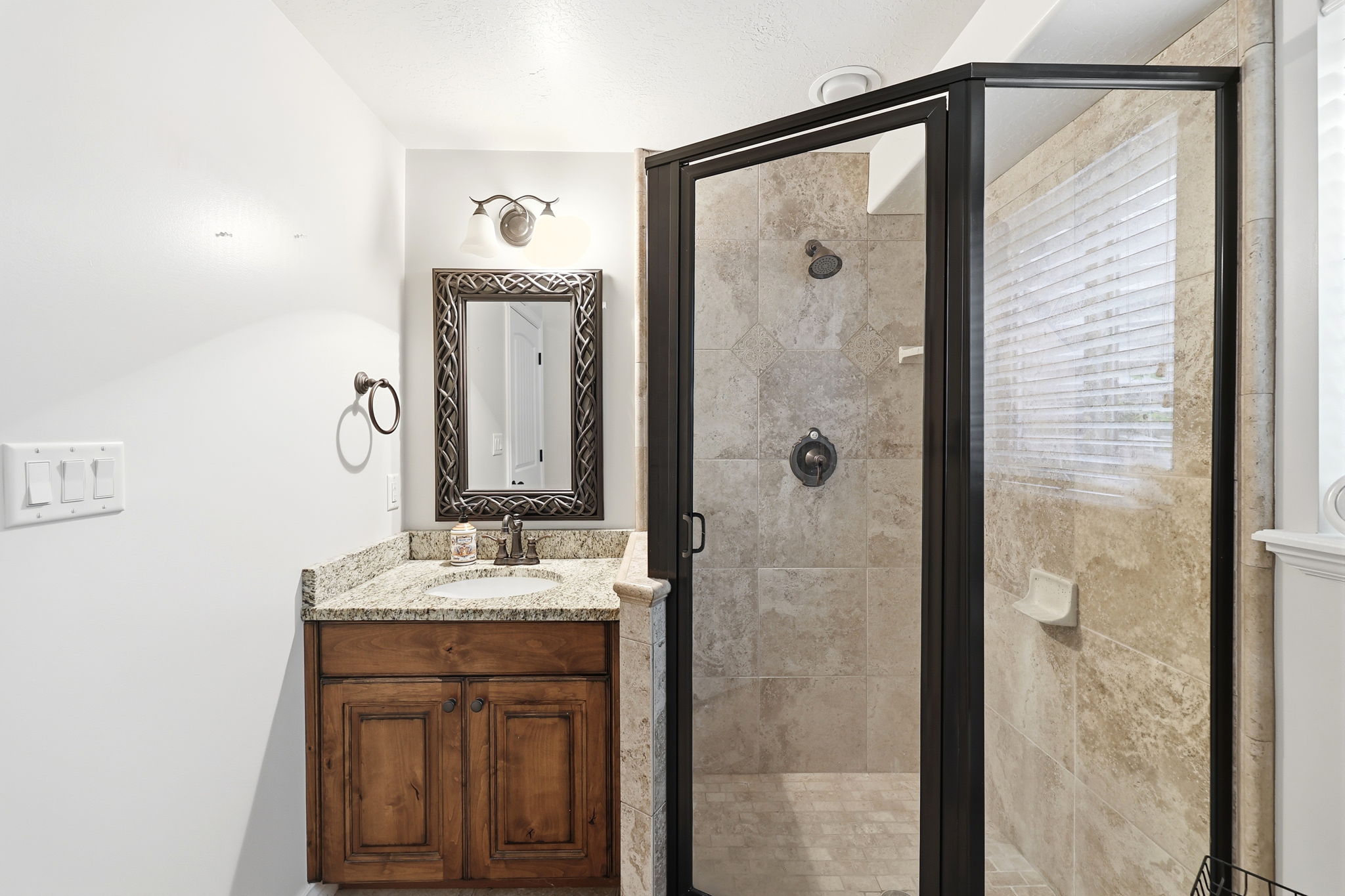 Bathroom featuring a walk-in shower with tiled walls and flooring, a dark-framed glass enclosure, and a window with blinds