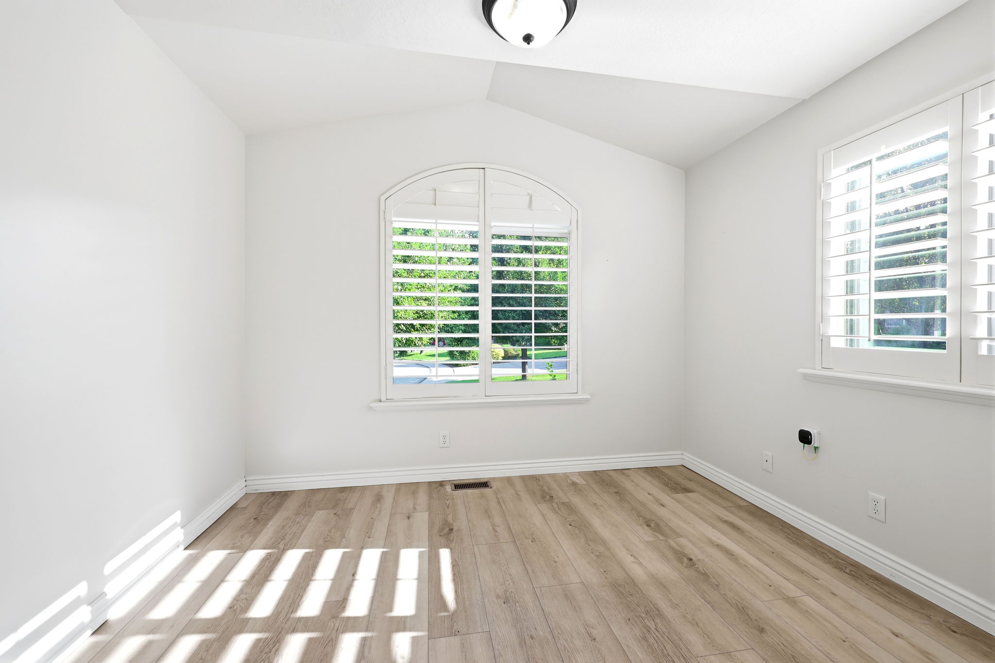 Room featuring a vaulted ceiling and light wood-finish flooring