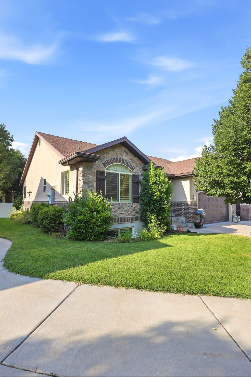 Stone and stucco exterior featuring a gabled roofline and arched window with shutters