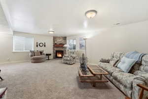Living area with a stone fireplace, a textured ceiling, and carpet flooring