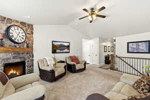 Carpeted living room featuring a ceiling fan and a fireplace