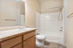 Bathroom with vanity, bathtub / shower combination, and stone finish flooring