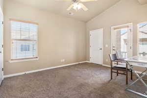 Unfurnished office featuring a ceiling fan, vaulted ceiling, and carpet flooring
