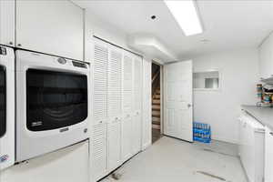 Laundry area with cabinet space, finished concrete flooring, and washing machine and dryer