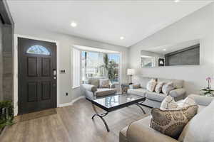 Living area featuring healthy amount of natural light, lofted ceiling, wood finished floors, and recessed lighting