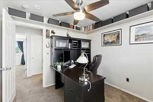 Office area featuring light carpet and a ceiling fan
