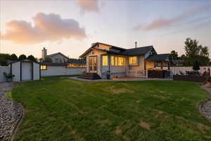 Back of house at dusk with a patio area, a fenced backyard, a storage shed, and entry steps