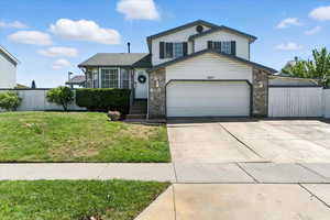 Tri-level home with stone siding, concrete driveway, and a garage