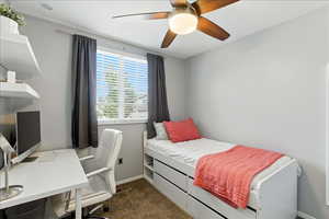 Bedroom with dark carpet, an office area, and ceiling fan