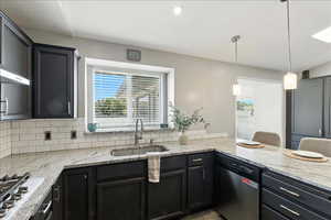 Kitchen with light stone countertops, stainless steel appliances, hanging light fixtures, tasteful backsplash, and a peninsula
