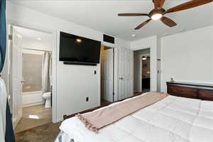 Carpeted bedroom featuring ensuite bath and a ceiling fan