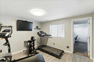 Workout area with light wood-type flooring and baseboards