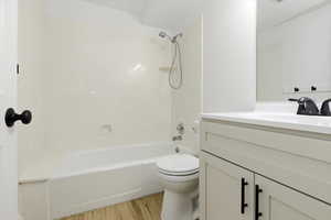 Full bath with vanity, light wood-style floors, and washtub / shower combination