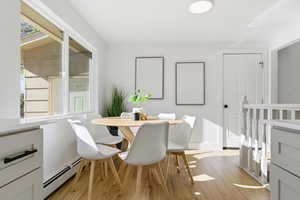 Dining room featuring baseboard heating, light wood finished floors, and healthy amount of natural light
