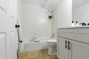 Full bathroom with vanity, tub / shower combination, and light wood-style floors