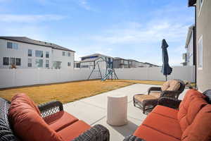 Fenced backyard featuring an outdoor living space, a playground, a patio area, and a residential view