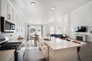 Kitchen featuring stainless steel appliances, a breakfast bar area, white cabinets, open floor plan, and dark wood finished floors