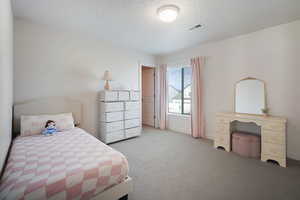 Bedroom with a textured ceiling and light colored carpet