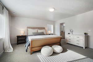 Carpeted bedroom featuring ensuite bath and a textured ceiling