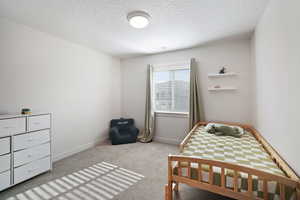 Bedroom featuring light colored carpet and a textured ceiling