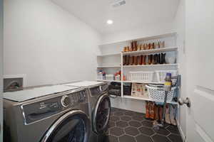 Laundry room with separate washer and dryer, dark tile patterned floors, and recessed lighting