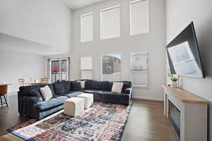Living area with dark wood-style flooring and a high ceiling