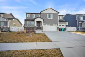 Craftsman-style house with a gate, an attached garage, driveway, board and batten siding, and stone siding