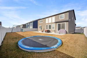 Rear view of property featuring a patio area, a fenced backyard, a playground, and a trampoline