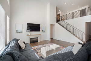 Living room featuring wood finished floors, a high ceiling, and a fireplace