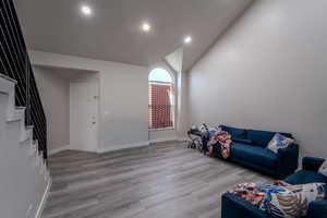 Living area with lofted ceiling, light wood finished floors, and recessed lighting