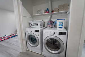 Laundry area with light wood finished floors and washer and clothes dryer