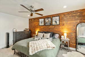 Bedroom featuring an accent wall, wooden walls, light carpet, a ceiling fan, and arched walkways