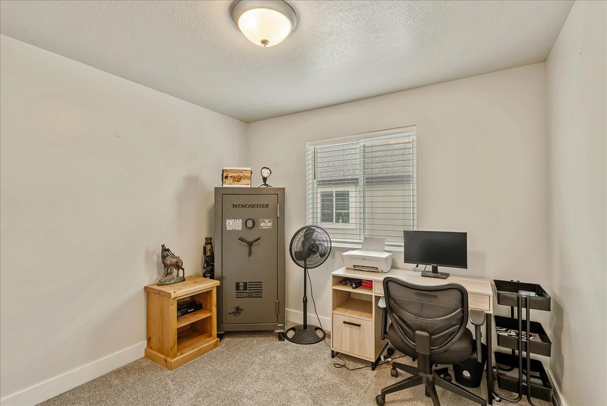 Home office featuring light colored carpet and a textured ceiling