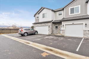 View of front of property featuring board and batten siding, stone siding, a shingled roof, and a garage