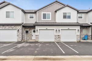 Craftsman-style house featuring stone siding, a shingled roof, board and batten siding, and an attached garage