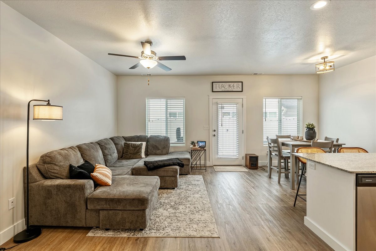 Living area featuring a textured ceiling, light wood finished floors, a ceiling fan, and healthy amount of natural light