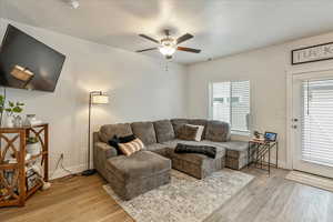 Living area featuring light wood-style floors, ceiling fan, and a textured ceiling