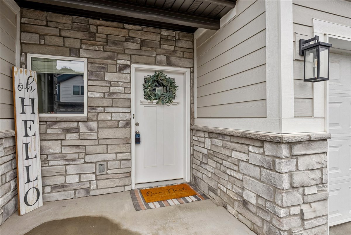 View of exterior entry with stone siding and a garage