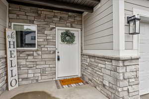 View of exterior entry with stone siding and a garage