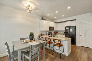 Kitchen featuring light stone counters, a peninsula, stainless steel appliances, light wood-style flooring, and a breakfast bar area