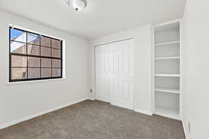 Unfurnished bedroom featuring dark carpet and a closet