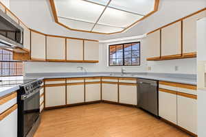 Two tone kitchen with two tone color scheme, stainless steel appliances, light wood-style floors, and light countertops