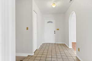 Entrance foyer featuring arched walkways and light tile patterned floors