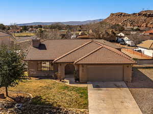 Mediterranean / spanish home with a chimney, a garage, a tile roof, driveway, and stucco siding