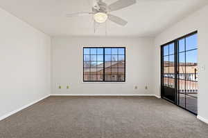 Spare room with ceiling fan and dark carpet