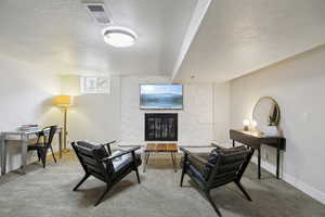 Living area featuring a fireplace, a textured ceiling, and carpet floors