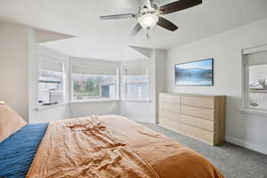 Bedroom featuring light carpet, a ceiling fan, and cooling unit