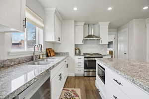Kitchen with white cabinets, dark wood-style floors, stainless steel appliances, light stone countertops, and recessed lighting