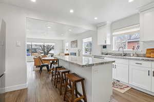 Kitchen featuring a kitchen island, white cabinetry, dark wood finished floors, a kitchen bar, and a fireplace