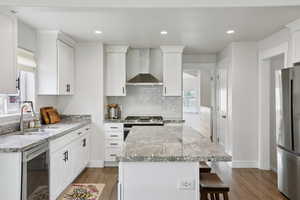 Kitchen featuring stainless steel appliances, a center island, light stone countertops, dark wood-type flooring, and recessed lighting